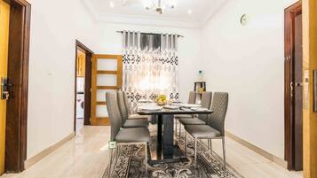 A dining area with a table, chairs, and a patterned rug.