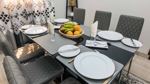 Una mesa lista para comer, con platos, cubiertos y un frutero.