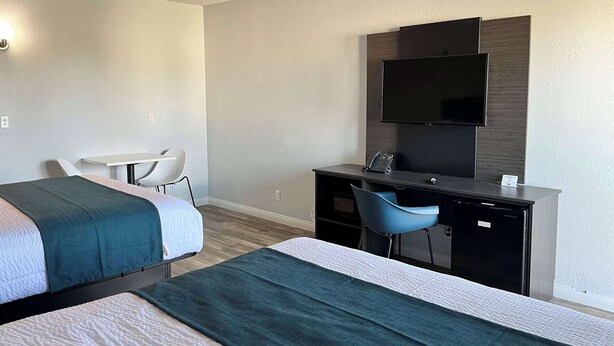 Habitación de hotel con dos camas, un escritorio, una silla, un televisor y un minibar.