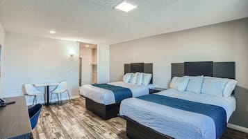 A hotel room with two beds, a desk, and a chair.