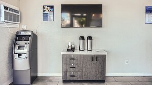 Un quiosco de autoservicio, una estación de café y un mueble pequeño con cajones.