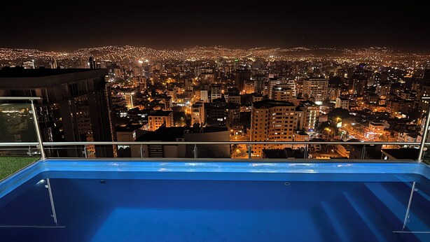 Una piscina en la azotea con vista a la ciudad de noche.