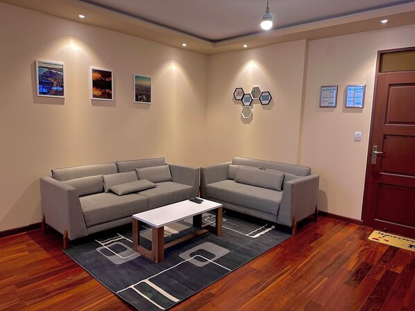 A modern living room with two grey sofas, a coffee table, and a wooden floor.
