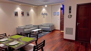 Una sala de estar moderna con comedor, sofás grises, piso de madera y obras de arte colgadas en la pared.