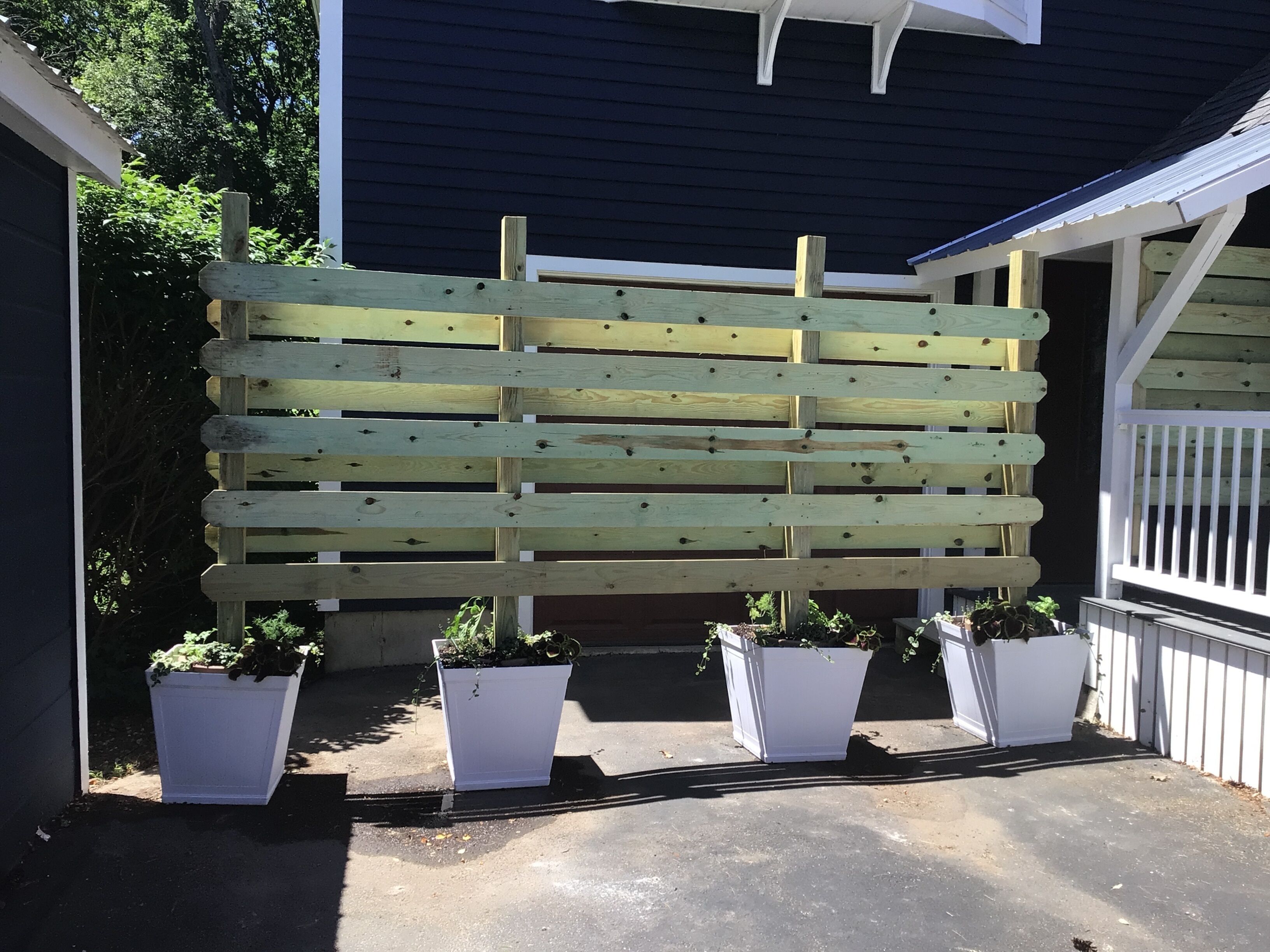A wooden fence with potted plants at its base.