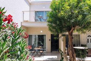 A two-story building with a balcony, outdoor seating, and a tree. - Procy-106 Venus Townhouse (Paphos)