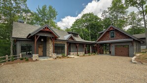 Une maison moderne de style ranch, avec une allée en gravier, des fondations en pierre et des éléments décoratifs en bois.