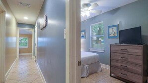 A hallway leading to a bedroom with a bed, dresser, and ceiling fan. - Delightful 2-bedroom, 1-bath Home Near Biloxi's Scenic Back Bay (Biloxi)