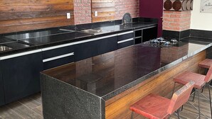 Uma cozinha moderna com uma ilha grande, banquetas de bar e uma parede de tijolos.