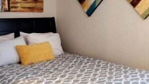 Ein Schlafzimmer mit einem Bett, einem Kopfteil, einem Bild an der Wand und zwei Wandbildern.