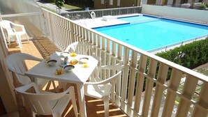 A balcony with a pool, white chairs, and a table set for dining. - Super Nice Apartment for 5 Guests With Pool and AC by Beahost Rentals (Caorle)