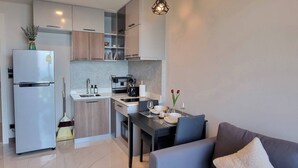 A modern kitchen with a built-in oven, a sink, and a dining area with a table and chairs. - B402- 1 Bedroom Condo With Sea View, Ao Nang Beach (Krabi)