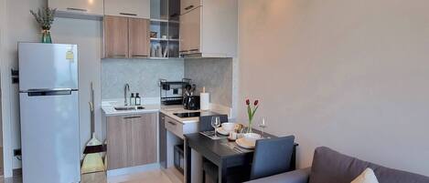 Una cocina moderna con horno empotrado, un lavaplatos y una zona de comedor con mesa y sillas.