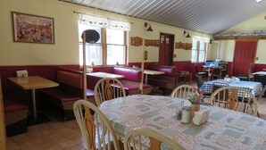 Ein Restaurant mit Sitzgelegenheiten in Form von Boxen, Tischen und Stühlen.