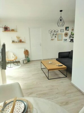 A modern living room with a wooden coffee table, a grey sofa, and a white door.