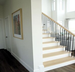 A staircase with wooden steps and black railings, leading to an upper floor. - 4 Bedroom Luxury Ocean View Beach House, Minutes To North Shore Beaches (Park Corner)