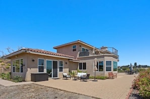 A two-story house with a patio area featuring outdoor furniture.