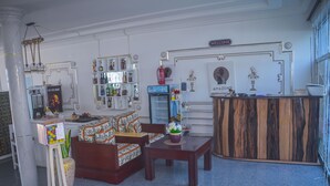 A lobby with a reception desk, seating area, and a display of various items. - Hôtel Amazone (Cotonou)