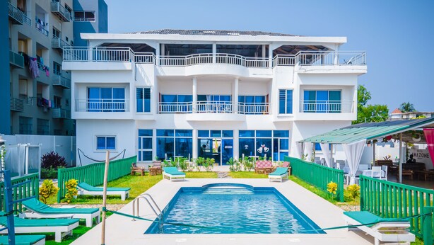 A multi-story hotel with a swimming pool, outdoor seating, and a restaurant. - Hôtel Amazone (Cotonou)