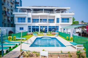 A multi-story hotel with a swimming pool, outdoor seating, and a restaurant. - Hôtel Amazone (Cotonou)