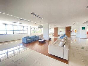 Un vestíbulo amplio con un sofá blanco, sillones azules y una mesa de centro.