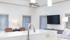 A modern kitchen with a central island, stainless steel sink, and pendant lighting.