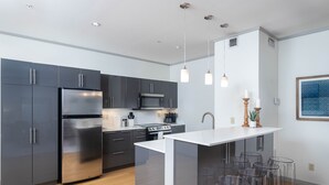 A modern kitchen with dark cabinets, stainless steel appliances, and a central island with bar stools.