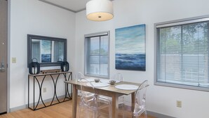 A modern dining area with a wooden table, clear chairs, and a pendant light.