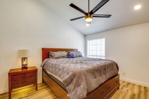 A bedroom with a bed, a nightstand with a lamp, a ceiling fan, and a window. - Pool & Hot Tub Access! Extended Stay in Chandler (Chandler)