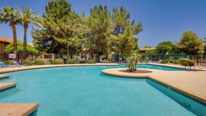 Une piscine à l’eau d’un bleu cristallin, entourée de palmiers et délimitée par une clôture, avec des chaises longues à l’intérieur.