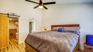Une chambre à coucher avec un lit, un plancher en bois, un ventilateur de plafond et une armoire avec une porte coulissante.