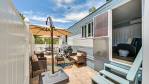 En overdækket terrasse med udendørs møbler, grill og springvand.