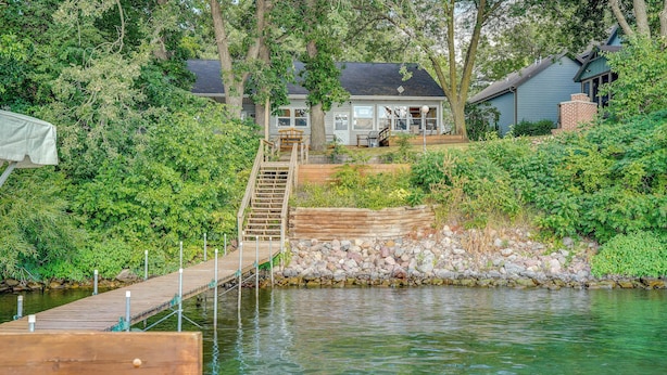 A wooden dock leading to a house with a stone wall and a staircase.