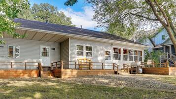 A single-story house with a front porch, a wooden deck, and a grill area.