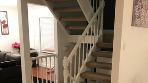 A staircase with white balusters leading to a landing, a dark-colored carpet, and a wooden floor. - Room in House - Modern Executive Master Bedroom (Alexandria)
