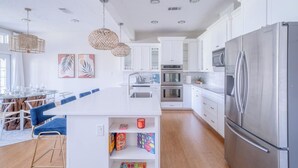 A modern kitchen with white cabinets, stainless steel appliances, and a central island with seating. - Professionally designed lake stay for families, friends, and celebrations (Montgomery)