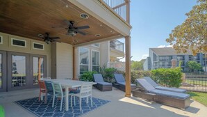 A covered patio with a table and chairs, lounge chairs, and a ceiling fan. - Professionally designed lake stay for families, friends, and celebrations (Montgomery)