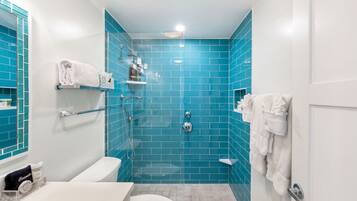 A bathroom with blue tiles, a white toilet, a sink, and a shower area.