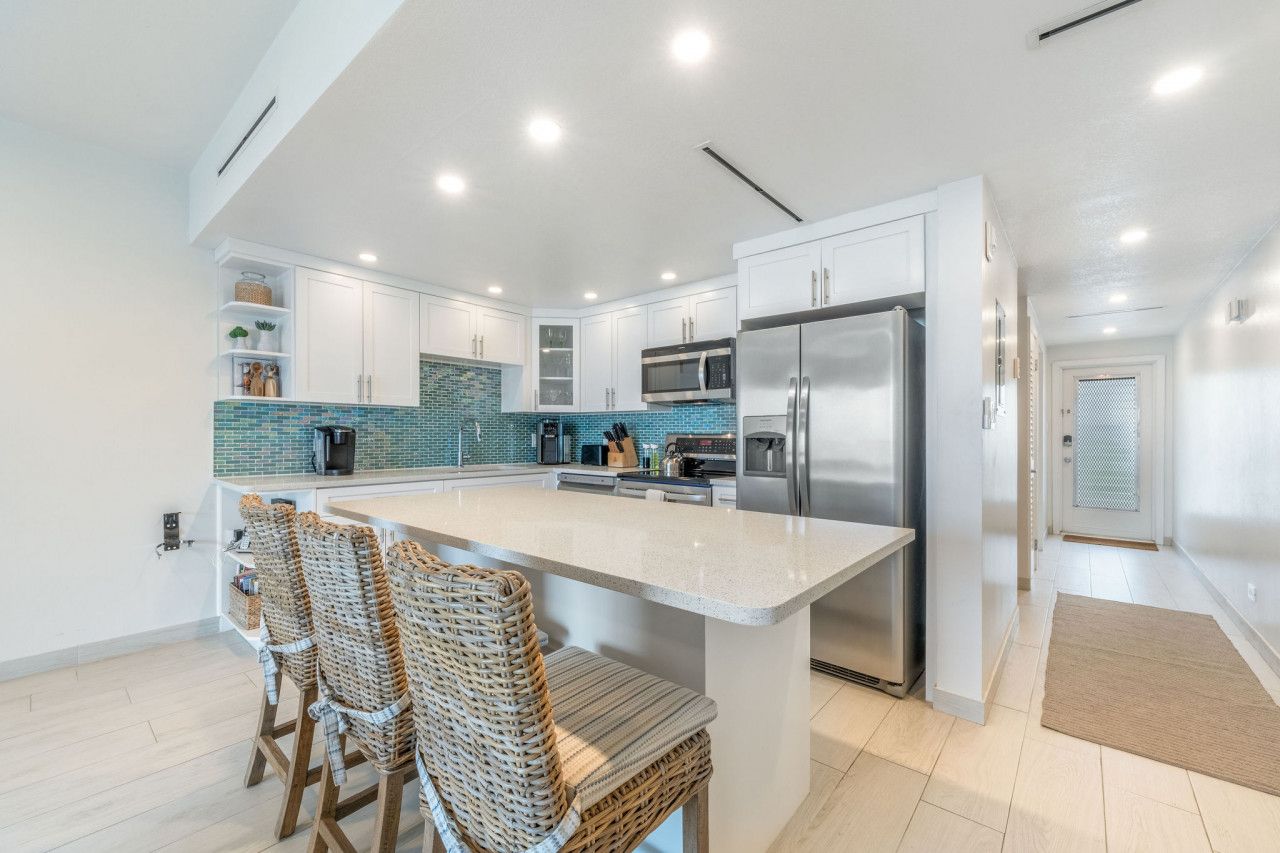 A modern kitchen with white cabinetry, a central island, and stainless steel appliances.