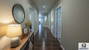 A hallway with a wooden bench, a lamp, and a mirror. - Foothills G-204 (Branson)