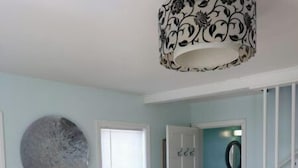Una habitació amb una cadira estampada, una decoració circular a la paret, una porta que dona a un bany i unes escales.