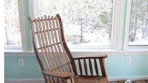 Una cadira bressol en una habitació amb grans finestres i un paviment de fusta.