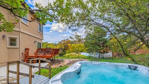 A hot tub in a backyard with a wooden deck and a wooden staircase leading up to it. - The Glen House, a lovely 4 bedroom home in Palmer Lake, with hot tub, and views! (Palmer Lake)