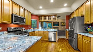 A modern kitchen with wooden cabinets, stainless steel appliances, and a granite countertop. - The Glen House, a lovely 4 bedroom home in Palmer Lake, with hot tub, and views! (Palmer Lake)