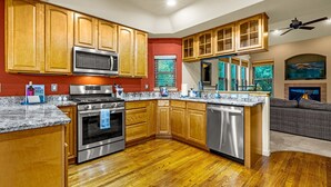 A modern kitchen with wooden cabinets, stainless steel appliances, and a marble countertop. - The Glen House, a lovely 4 bedroom home in Palmer Lake, with hot tub, and views! (Palmer Lake)