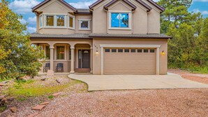 A two-story house with a garage, a covered porch, and a landscaped driveway. - The Glen House, a lovely 4 bedroom home in Palmer Lake, with hot tub, and views! (Palmer Lake)