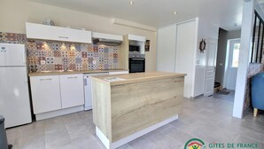 A modern kitchen with white cabinets, a wooden island, and a colorful backsplash. - L'avocette - Damgan - Gîte (DAMGAN)