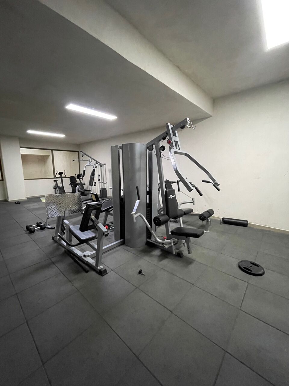 A gym with exercise equipment, a mirror, and a tiled floor.