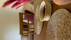 Un coin repas avec une table en bois, des sets de table en fibres tressées et une vue sur la cuisine et l’espace de vie.