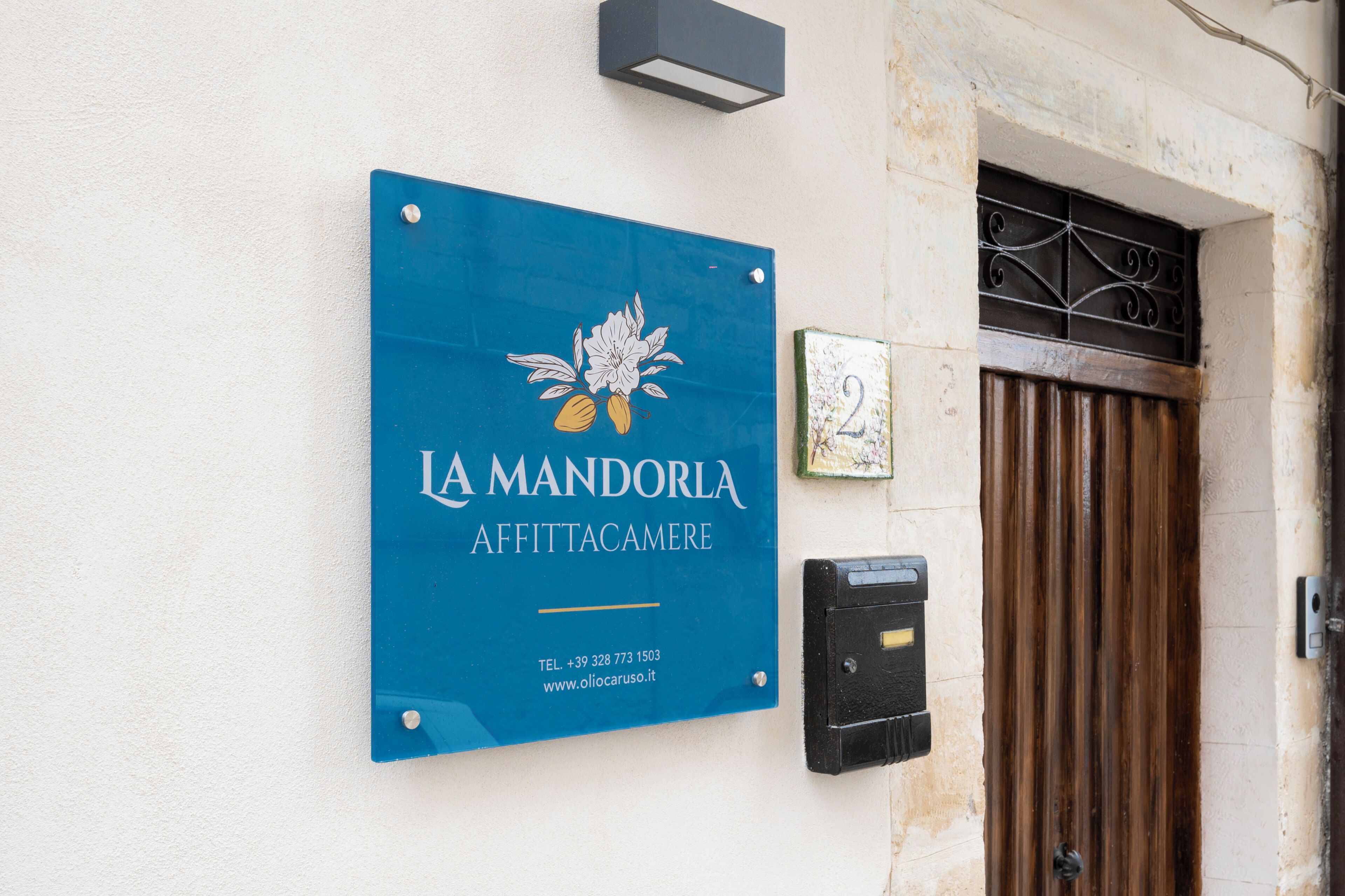 Um sinal azul com 'IA MANDORIA AFFITTACAMERE' e informações de contato.